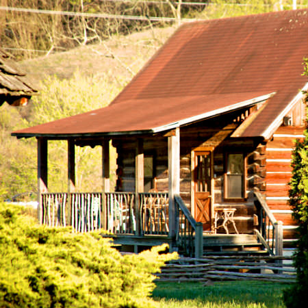 A sunny view of a quaint rustic reddish-brown wood cabin 