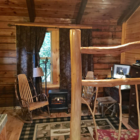 Two natural rustic rocking chairs sit by a window with partially drawn brown curtains